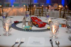 a toy car is sitting on top of a table with silverware and wine glasses