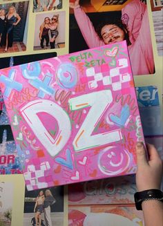 a person holding up a pink box with pictures on it and the word d is spelled in white letters