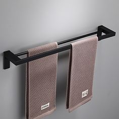 two towels hanging on a towel rack in a bathroom with grey walls and black metal bars