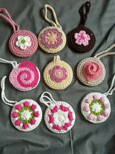 six crocheted purses are arranged on a gray surface with pink, white and green flowers