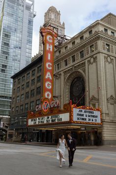 two people walking in front of the chicago theatre