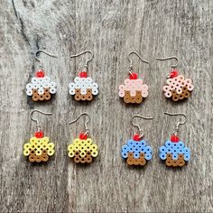 six pairs of earrings made out of perler beads on a wooden surface with an apple in the middle