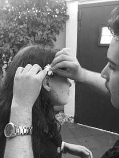 a man helping a woman put a flower on her hair