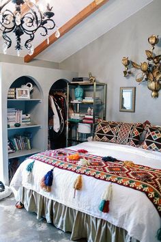 a bed sitting in a bedroom under a chandelier next to a book shelf