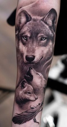 an arm tattoo with two wolfs and a feather on the left side of it