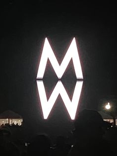 a large white sign on the side of a building at night with people standing around it