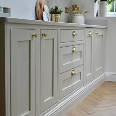 a kitchen with white cabinets and gold pulls on the handles, drawers and cupboards