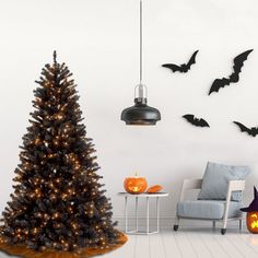 a living room decorated for halloween with bats on the wall and a black christmas tree