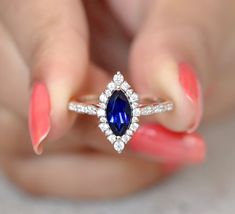 a woman's hand holding an engagement ring with a blue and white stone in it