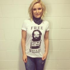 a woman standing in front of a brick wall wearing a t - shirt that says free