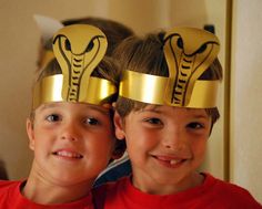 two young boys wearing gold crowns with cobra headbands on their heads in front of a mirror