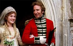 a man and woman in wedding attire standing next to each other on the balcony of a building