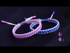 two braided bracelets sitting on top of a black table next to each other