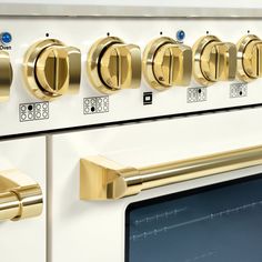 a white stove with gold knobs and brass handles