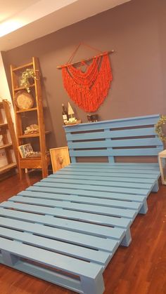 a blue bed frame sitting on top of a hard wood floor next to a book shelf