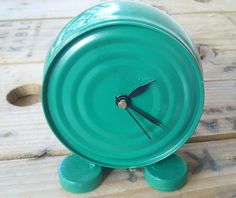 a green clock sitting on top of a wooden table