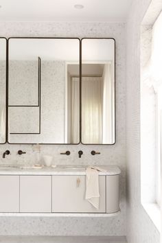 a bathroom with two sinks and three mirrors