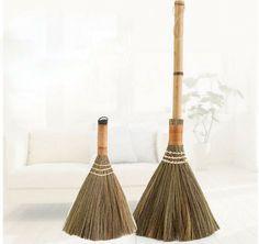 two brooms sitting next to each other in front of a white couch