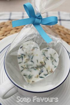 two heart shaped cookies in a teacup on a plate with a blue ribbon tied around it