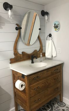 a bathroom with a sink, mirror and toilet paper dispenser