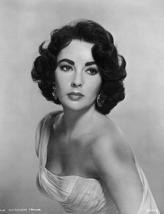 an old black and white photo of a woman in a dress with her hair up