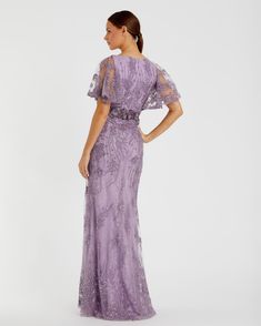 a woman in a long purple dress with sheer sleeves and an open back, looking at the