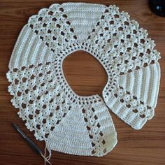 three crocheted doily on a wooden table with yarn and scissors next to them