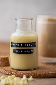 a bottle of milk sitting on top of a wooden table next to a cup of coffee