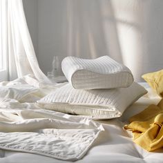 pillows and blankets on a bed with white sheets