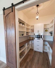 an open door leading to a kitchen with white cabinets and wood flooring on the walls