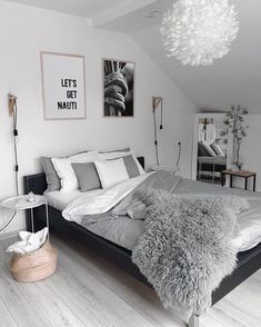 a bedroom with white walls and wooden flooring is decorated in black and white tones