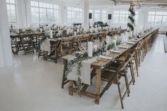 a long table with white linens and greenery is set up for an event