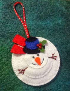 a felt snowman ornament hanging on a green surface