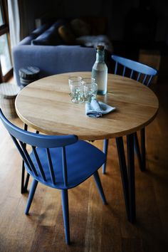 a table with two chairs and a bottle on top of it in front of a couch