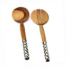 two wooden utensils with black and white stripes on them, one is holding a spoon