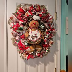 a christmas wreath hanging on the front door with a teddy bear and cake in it