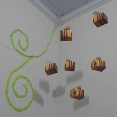 several pieces of wood are hanging from the ceiling in front of a white wall with green streamers