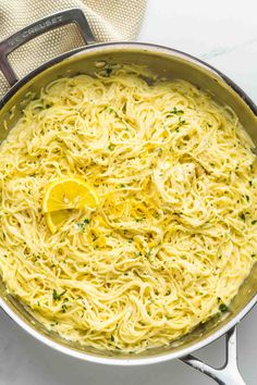 a pan filled with spaghetti and lemon wedges