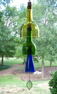 the wine - chime sign is hanging in front of some trees and grass with a bell on it