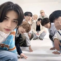 a group of young men sitting next to each other in front of a white wall