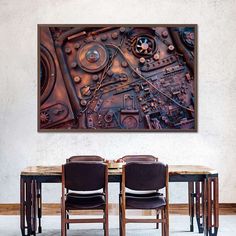 a dining room table with chairs and a large metal art piece on the wall