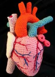 a crocheted heart with an arrow and two smaller hearts attached to the side