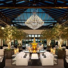 an indoor dining area with chandelier and white couches in front of windows