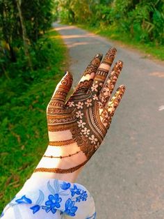 a woman's hand with henna on it and green grass in the background