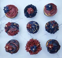 nine cupcakes decorated with red, white and blue icing on a marble surface