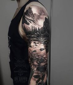 a man's arm with an image of mountains and trees on it