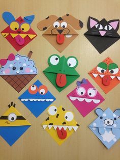 a group of different colored paper animals on a wooden table with one animal sticking out of it's mouth