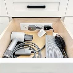 a drawer with hair dryers and other items in it