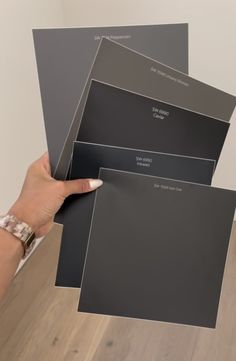 a person holding up some gray paint samples