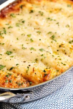 a casserole dish with cheese and parsley on the top is ready to be eaten